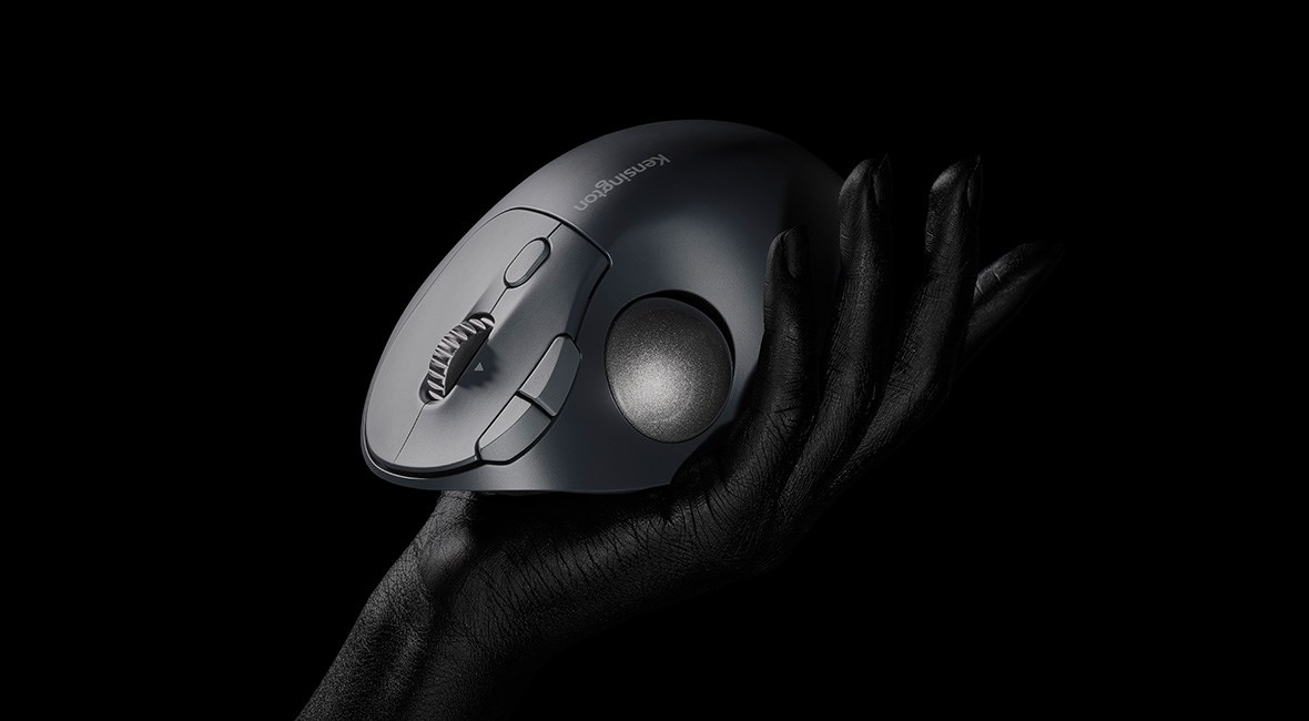 A black Kensington EQ trackball held in a hand against a dark background. 